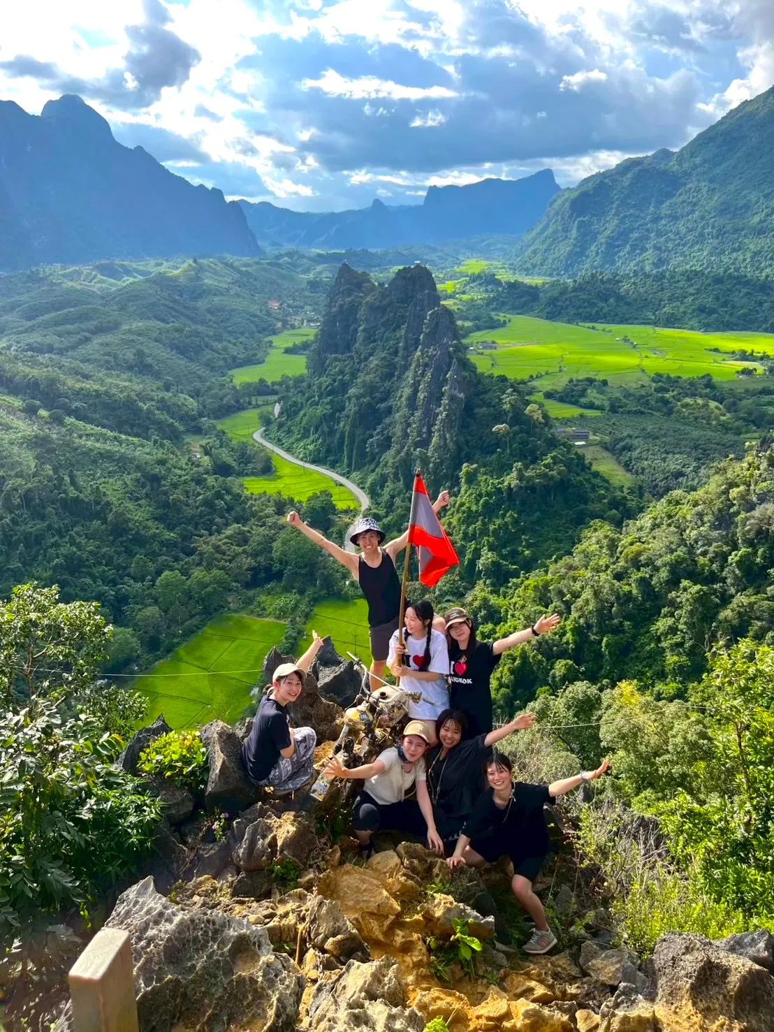 ラオスの山々を背景に国旗を掲げる参加者