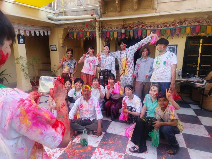 ホーリー祭の前、色粉でカラフルになった参加者たちが写真撮影をしている様子