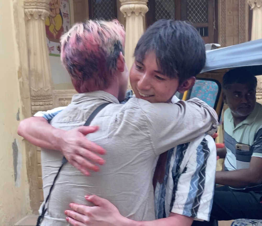 ホーリー祭で色粉に染まったまま日本に帰国する参加者同士が別れのハグをする様子