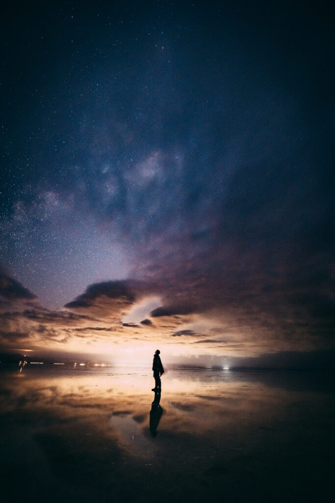 ウユニ塩湖で星空を眺める参加者のシルエットと鏡のような水面