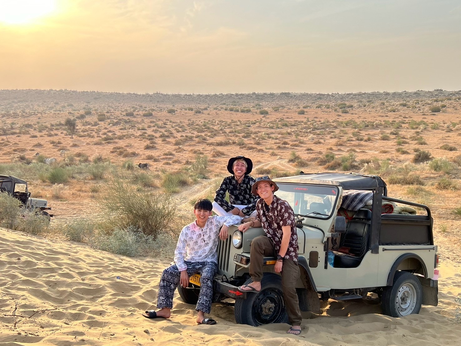 ジャイサルメールの砂漠で乗ってきたジープにもたれかかる参加者の3人の男の子